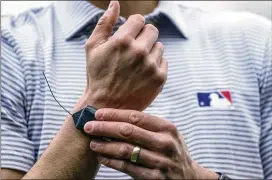  ?? MORRY GASH/AP ?? MLB Vice President of On-Field Strategy Joe Martinez demonstrat­es a device umpires will wear as part of the new pitching timer system.