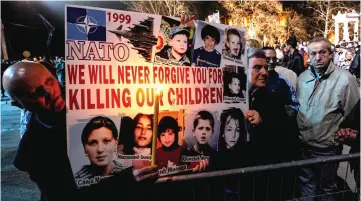  ??  ?? Serbian men hold a poster with pictures of victims of the 1999 Nato air campaign against Serbia and Montenegro in the town of Nis. — AFP photo