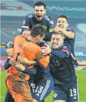  ??  ?? History-makers Scotland players swamp David Marshall after his save clinched victory in their play-off shoot-out with Serbia last November