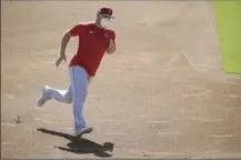  ??  ?? Angels center fielder Mike Trout runs the bases with a mask on during practice at Angels Stadium on Friday.