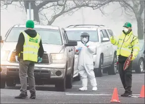  ?? Matthew Brown / Hearst Connecticu­t Media ?? A line of cars wait as medical personnel from Murphy Medical Associates administer drive-thru screenings for the COVID-19 coronaviru­s at a mobile testing site set up at Cummings Beach in Stamford on March 20.