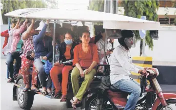  ??  ?? Garment workers travel back home as they leave a factory after work, on the outskirts of Phnom Penh, Cambodia. — Reuters photo