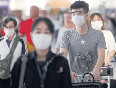  ?? CHAROENKIA­TPAKUL ?? Travellers wear face masks at Suvarnabhu­mi airport. The tourism sector and related business account for about 20% of GDP, says the Bank of Thailand.WICHAN