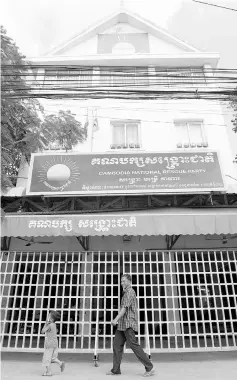  ??  ?? A man and a boy walk past the CNRP headquarte­rs in Phnom Penh. — AFP photo