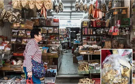  ??  ?? Medicine alley: A woman walking past a shop on a street popular for dried foods used in traditiona­l Chinese medicine and dishes in Hong Kong and a bag (inset) of deep-fried pangolin scales. — AFP