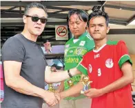  ??  ?? PENJARING gol kemenangan Pelajar Indonesia, Ilham (kanan) menerima hadiah yang disampaika­n bekas pemain import Pahang dari Australia, Alan Davidson.