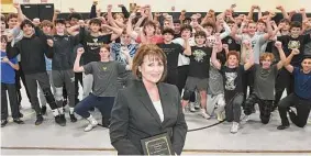  ?? Ned Gerard/Hearst Connecticu­t Media ?? Diane Fulco poses in front of the wrestling team with the Lasting Impact Award she is receiving for years of volunteeri­ng and support of the Trumbull High School wrestlers, seen here in Trumbull on Friday.