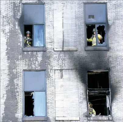  ?? Darrell Sapp/Post-Gazette ?? The windows and exterior bricks at Midtown Towers along Penn Avenue show damage from smoke and flames after a seven-alarm fire in Downtown early Monday. Visit post-gazette.com for a video report.