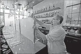  ?? [RICK BOWMER/THE ASSOCIATED PRESS] ?? Mark Sylvester takes down a partition known as a “Zion Curtain” at Current Fish & Oyster in Salt Lake City on Saturday. A new Utah law is making wine, liquor and higher-alcohol beer more expensive. It also allows some restaurant­s to remove the...