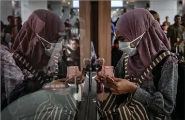  ??  ?? A passenger wears a protective mask at a money exchange after arriving at Adisucipto Airport in Yogyakarta, Indonesia