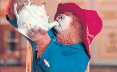  ?? ?? Paddington, voiced by Ben Whishaw, enjoys a cuppa (sort of) while famously meeting the Queen