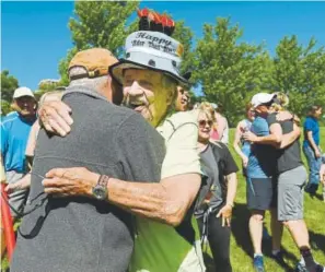  ?? Hyoung Chang, The Denver Post ?? Fitness pioneer John Gillingham gets a hug at his 90th birthday celebratio­n on June 2 at George Wallace Park, where he led his last fitness class.