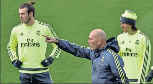  ??  ?? ATENTOS. Bale y Modric escuchan las indicacion­es de Zidane durante un entrenamie­nto del Real Madrid.