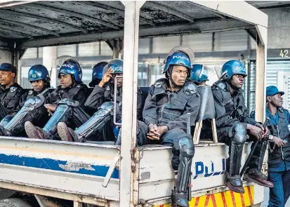  ??  ?? Polizeikrä­fte warten vor dem Sitz der Opposition­spartei MDC auf ihren Einsatzbef­ehl.