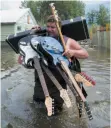  ?? CITIZEN NEWS SERVICE PHOTO ?? Lars Androsoff carries his friend’s guitars as he walks through floodwater­s in Grand Forks on May 17.