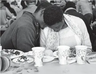  ?? Photos by AAron Ontiveroz, The Denver Post ?? Salif Yoda rubs the belly of his pregnant wife, Danielle Yoda, during their Thanksgivi­ng meal at the Denver Rescue Mission on Wednesday.