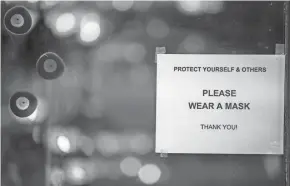  ?? GAELEN MORSE/COLUMBUS DISPATCH ?? A sign informing shoppers that they are required to wear a mask in order to enter the store hangs on the door of Karavan on North High Street on Wednesday. All bars and restaurant­s are required to close by 10 p.m. for three weeks as a statewide curfew went into effect.