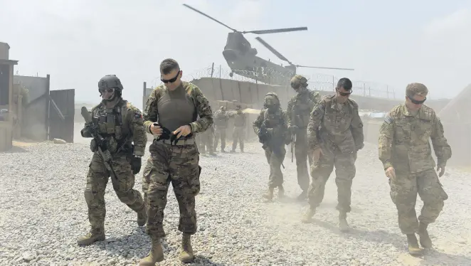  ??  ?? U.S. army soldiers walk as a NATO helicopter flies overhead in the Khogyani district in the eastern province of Nangarhar, Aug. 13, 2015.