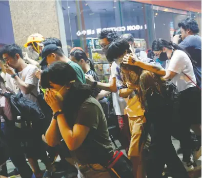  ?? TYRONE SIU / REUTERS ?? Anti-extraditio­n bill protesters react after the police fired tear gas on Thursday in Hong Kong.