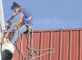  ?? CONTRIBUTE­D ?? While working high in the air, Jamie Long removes a safety anchor from a church roof.