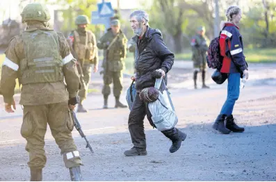  ?? AP ?? A man, who left a shelter in the Metallurgi­cal Combine Azovstal, walks to a bus between servicemen of Russian Army and Donetsk People’s Republic militia in Mariupol, in territory under the government of the Donetsk People’s Republic, eastern Ukraine.