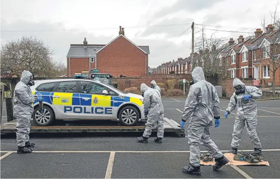  ?? Picture: Getty, ?? Military personnel wearing protective suits remove a police car and other vehicles from a public car park as they continue their probe into the nerve agent attack.