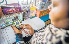  ?? /Bloomberg ?? Life cycle: A vendor at a vegetable stall in Nairobi checks her phone for a purchase order made to Twiga Foods. Blockchain would enable customers to track produce from farm to shelf.