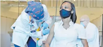  ?? Registered nurse La Tanya Forbes, right, is inoculated with the Pfizer-BioNTech COVID-19 vaccine by RN Cheryl Birmingham, left, at Memorial Healthcare System on December 14, 2020, in Miramar, Fla. Picture: AP ??