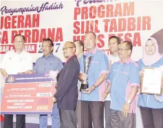  ??  ?? Ismail Sabri (left) presenting the main prize to Labuan’s Kampung Layang Layangan, witnessed by Musa.