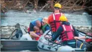  ??  ?? Parents huddle with their children on their boat as rescuers from the Friendship Dive Rescue Unit prepare to tow them back to safety after getting stuck on the Schuylkill River’s Black Rock Dam Thursday.