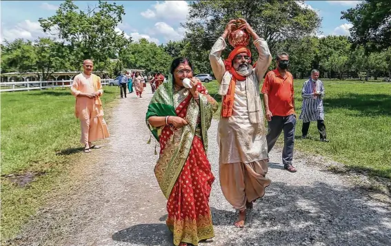  ?? Photos by Leslie Plaza Johnson / Contributo­r ?? Arati Nanda Pati, left, and Orissa Culture Center leader Debananda Pati walk to the main building with a representa­tion of newly incarnated deities during Ratha Yatra.