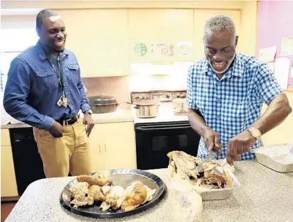  ?? AMY BETH BENNETT/STAFF PHOTOGRAPH­ER ?? Independen­t living case managers Peter Vedrine, left, and Lennox Spencer carve turkeys for the annual family-style holiday meal at Covenant House in Fort Lauderdale.