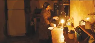  ?? (Mohammed Salem/Reuters) ?? A PALESTINIA­N WOMAN washes dishes in the kitchen of her Gaza City home during a power cut in April.