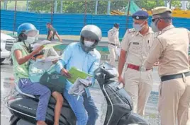  ??  ?? Police personnel screen ask commuters for identity cards and permits at the Sirhaul toll plaza in Gurugram on Sunday. YOGENDRA KUMAR/HT PHOTO