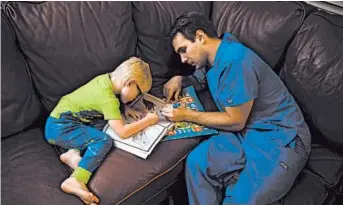  ??  ?? Spencer Cushing, a nurse who works in St. Jude Medical Center’s COVID-19 unit, helps his son, James, color.