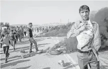  ?? Majdi Mohammed / Associated Press ?? A Palestinia­n demonstrat­or displays a photo of 18-month-old Ali Dawabsheh, who was killed in an arson attack last week. Ali’s father, Saad Dawabsheh, also died from burns suffered in the blaze.