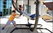  ?? NWA Democrat-Gazette/DAVID GOTTSCHALK ?? Cruze Kirk, 4, pushes his mother, Katie, in one of the swinging chairs Monday on the rooftop patio and garden area at Fayettevil­le Public Library. The library is currently in its preliminar­y design phase for expansion onto property next door.