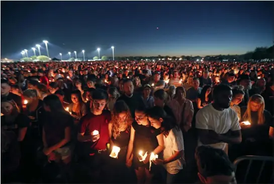  ?? GERALD HERBERT — THE ASSOCIATED PRESS FILE ?? People attend a candleligh­t vigil for the victims of the shooting at Marjory Stoneman Douglas High School in Parkland, Fla., on Feb. 15, 2018. After a gunman murdered 14students and three staff members at the high school, their families were left with a burning question: How do we go on with our lives while honoring our loved one’s memory?