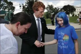  ?? THE ASSOCIATED PRESS ?? Rep. Joe Kennedy, D-Mass., center, shakes hands with an 11-year-old transgende­r girl who goes by the name Blue, whose parent is an airman at Ramstein Air Base, after Blue and her mother Jess Girven, left, attended Kennedy’s event in support of...