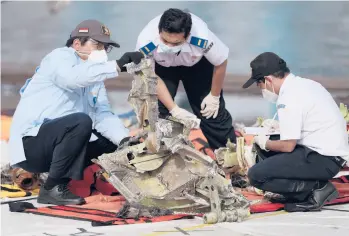  ?? DITAALANGK­ARA/AP ?? Indonesia plane crash: Investigat­ors inspect pieces of downed Sriwijaya Air flight SJ-182 Thursday in Jakarta, Indonesia. Authoritie­s ended the search for the wreckage of the plane that nosedived Jan. 9 into the Java Sea, killing all 62 people on board. A limited search for the missing memory unit from the cockpit voice recorder will continue.