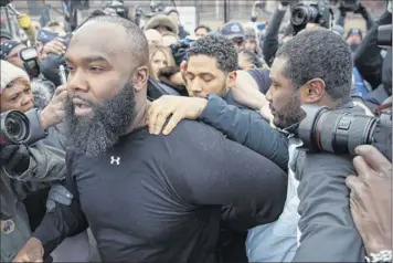  ?? Kamil Krzaczynsk­i / Associated Press ?? “Empire” actor Jussie Smollett, rear center, leaves Cook County jail following his release, Thursday in Chicago. Smollett is charged with disorderly conduct and filling a false police report when he said he was attacked in downtown Chicago by two men who hurled racist and anti-gay slurs and looped a rope around his neck, a police official said.