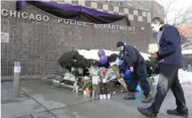  ?? | AP ?? Todd Markshon ( left) and Nick Moulopoulo­s bring flowers to a memorial for Chicago Police Cmdr. Paul Bauer outside Near North District headquarte­rs Wednesday.