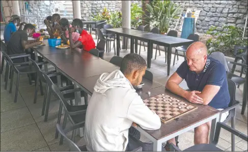  ?? (AP/Renata Brito) ?? British hotel director Calvin Lucock plays checkers with a Moroccan migrant at the Holiday Club Puerto Calma hotel in Puerto Rico de Gran Canaria, Spain.