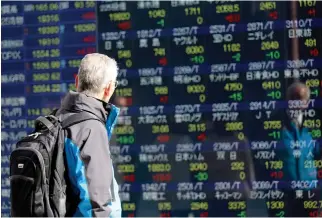  ??  ?? A man looks at an electronic stock board of a securities firm in Tokyo, on Thursday. (AP)