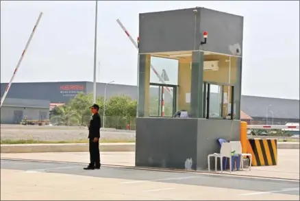  ?? HENG CHIVOAN ?? An employee stands by the gate of the Kerry WorldBridg­e Logisitics free trade zone in Kandal province yesterday.