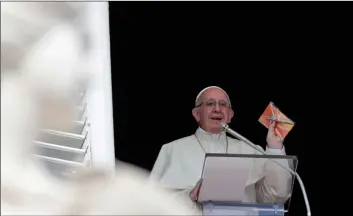  ??  ?? Pope Francis shows a crucifix during the Angelus noon prayer he delivers from the window of his studio overlookin­g St. Peter’s Square at the Vatican, on Sunday. AP PhoTo/AleSSAndrA TArAnTIno