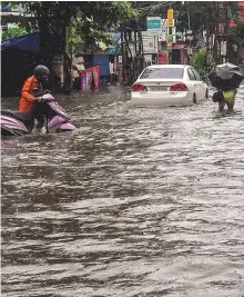  ?? PTI ?? A pedestrian wades across a waterlogge­d street after heavy rains in Kochi, Kerala, yesterday.