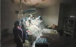  ?? — AP ?? Shady situation: Dr Duda and his team performing a surgery with only a headlamp for light after a blackout at a hospital in Lviv.