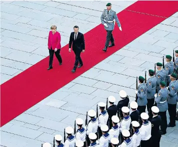  ??  ?? French President Emmanuel Macron is welcomed by German chancellor Angela Merkel and, above, arrives at the Chanceller­y in Berlin