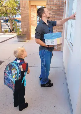  ?? GREG SORBER/JOURNAL ?? Christophe­r Bostick checks a list of classroom assignment­s as he and son, Landyn Bostick, 6, arrive Monday for the first day of school at Mitchell Elementary.